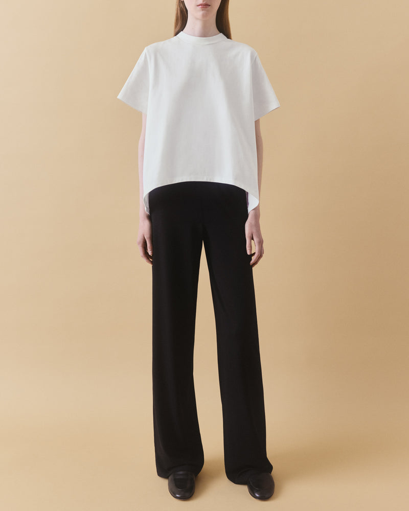 Off-white oversized organic cotton t-shirt with curved hem, full length styled with black trousers and leather loafers – Dhoemi Bend